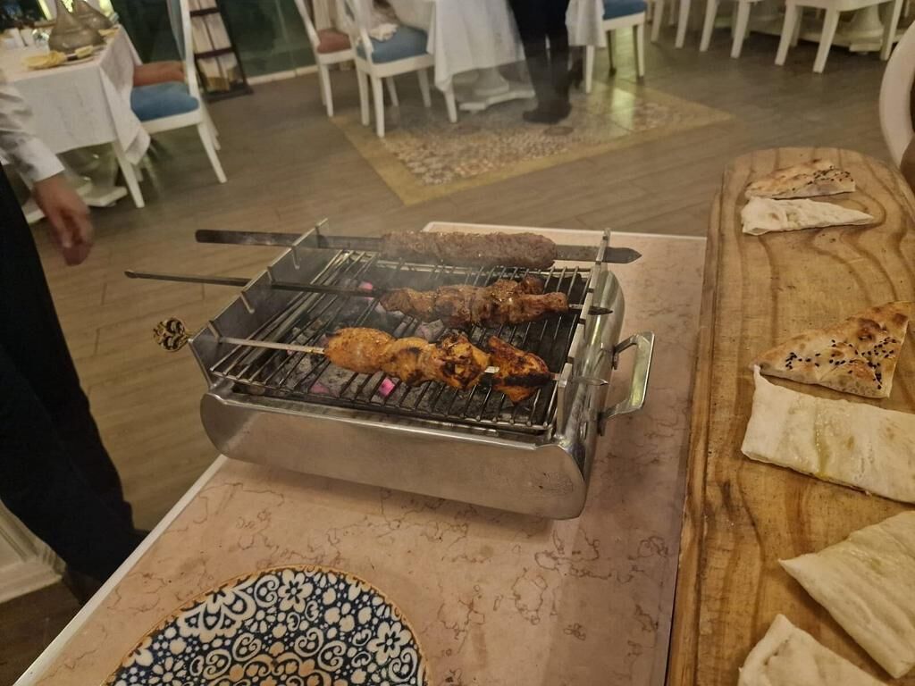A grill with skewered meat being cooked outdoors.