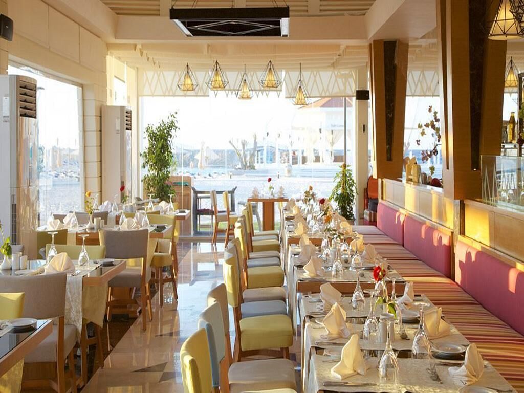 Un ristorante con diversi tavoli apparecchiati per gli ospiti, ampie finestre che offrono vista sulla città e lampadari a sospensione.