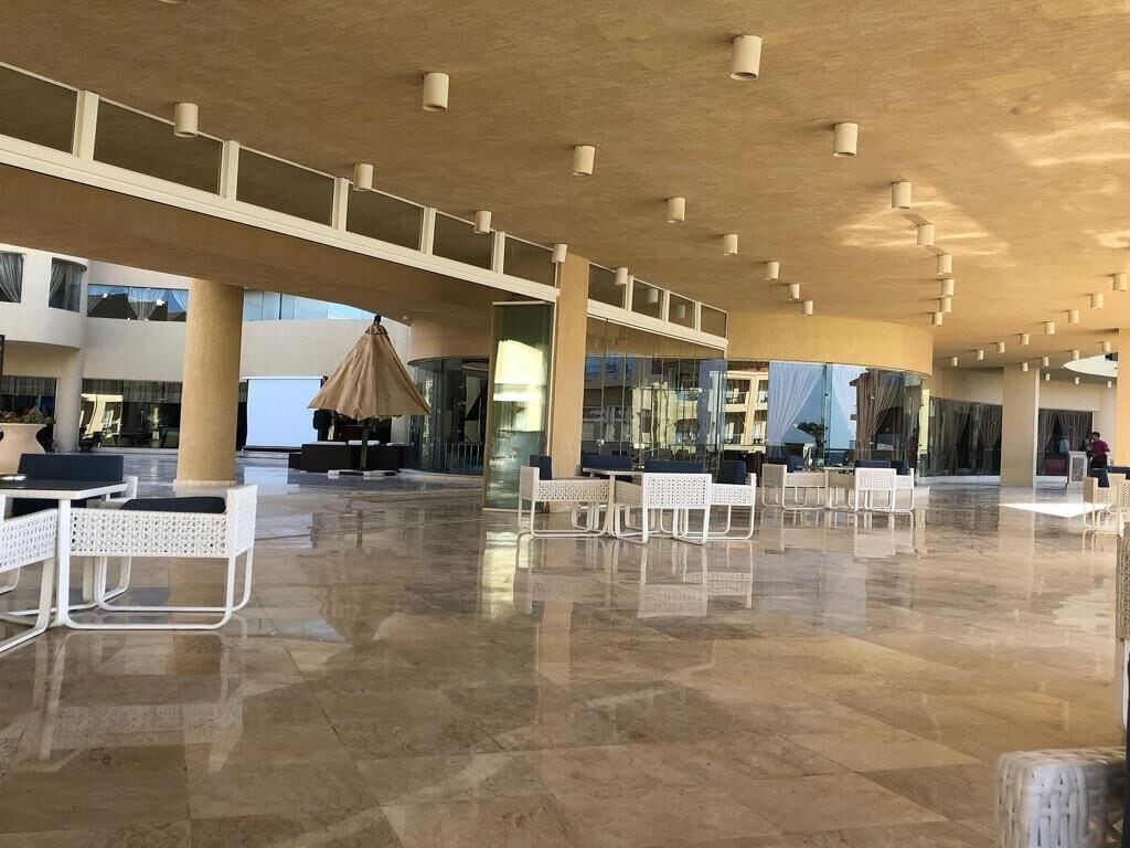A spacious lobby with a high ceiling, large windows, and a polished floor.