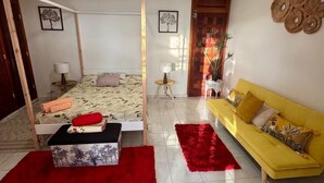 Une chambre à coucher avec un lit à baldaquin, un canapé jaune et un tapis rouge.