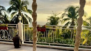 Un fauteuil suspendu en bois offrant une vue sur les palmiers et doté d’une balustrade.