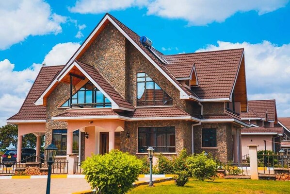 Una casa moderna con fachada de piedra, múltiples ventanas y un césped bien cuidado.