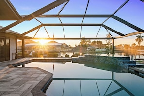 A modern infinity pool with a glass ceiling, reflecting the surrounding landscape and palm trees.