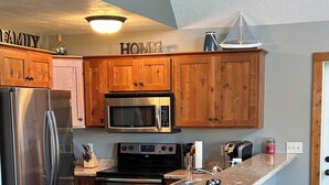 Una cocina moderna con armarios de madera, electrodomésticos de acero inoxidable y una zona de bar con taburetes.