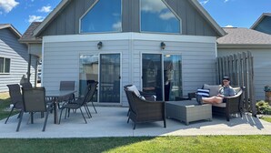 Una casa moderna con un patio amplio, muebles de exterior y cielo despejado.