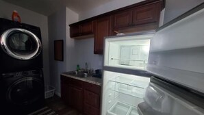 Una cocina con lavadora, refrigerador, armarios de madera y una encimera con lavamanos.