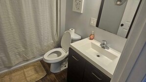 Un baño con inodoro, lavamanos y espejo.