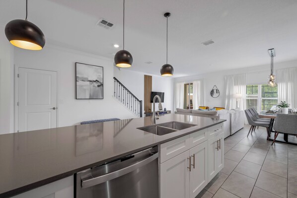 Una cocina moderna con una isla central, electrodomésticos de acero inoxidable e iluminación colgante.
