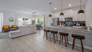 A modern kitchen with white cabinets, a central island with bar stools, and pendant lighting. - SL4359 - 5BR house with private pool in Kissimmee (Kissimmee)