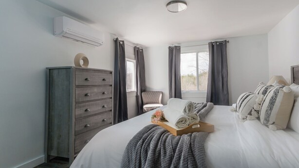 A bedroom with a bed, a dresser, a chair, and a window with curtains.