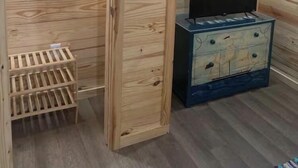 A wooden-paneled room with a television on a dresser and a wooden rack. - Custom built cool cabin with AC in Holiday Beach. Not a converted shed. (Rockport)
