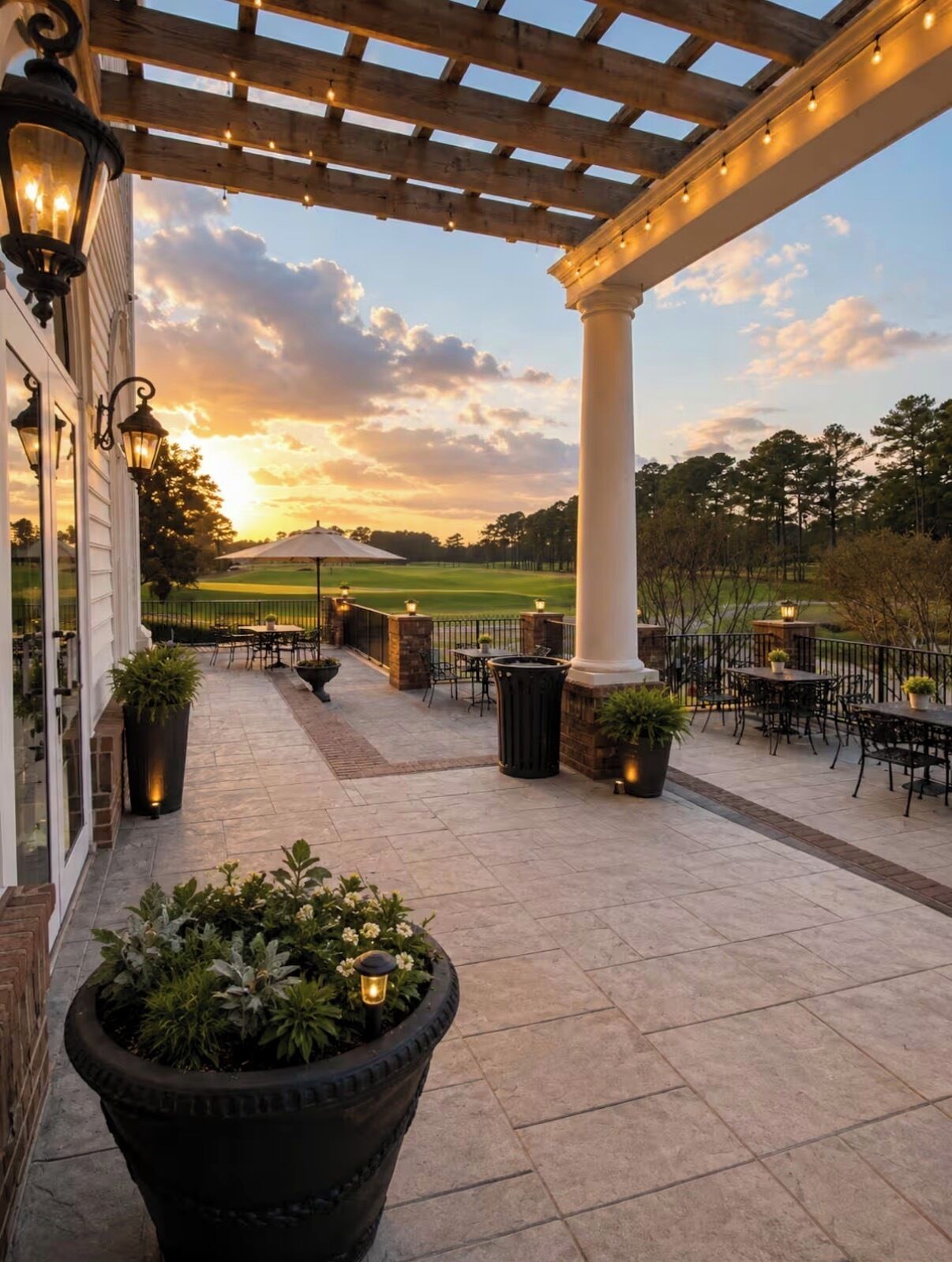 An outdoor patio with a pergola, tables, chairs, and potted plants.