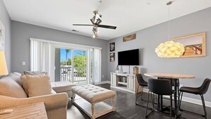 A modern living room with a sofa, ottoman, dining table, chairs, and a ceiling fan. - NEWLY RENOVATED 2BR Golfer's Paradise Condo at World Tour (Myrtle Beach)