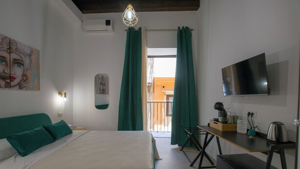 Une chambre à coucher avec un lit, un bureau, une télévision et une vue sur l’extérieur.