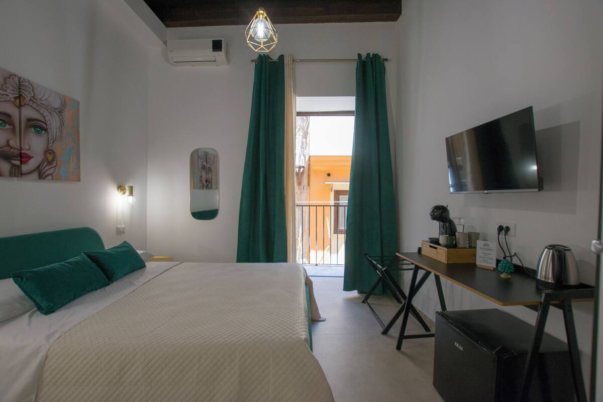 Une chambre à coucher avec un lit, un bureau, une télévision et une vue sur l’extérieur.
