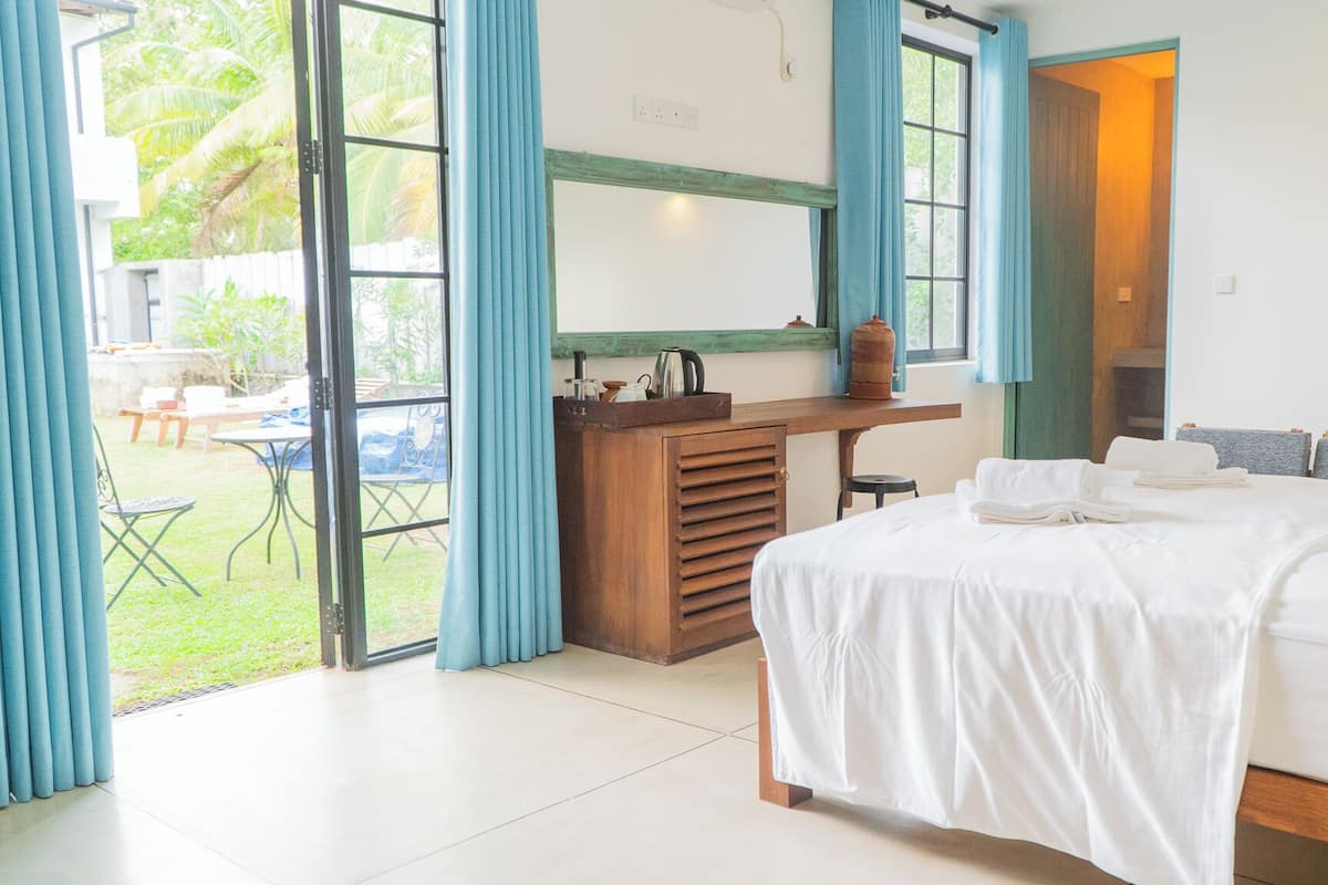 A bedroom with a bed, a desk, and a view of the outdoors.