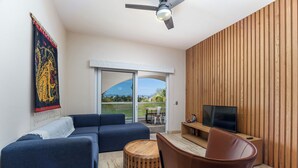 Un salon moderne avec un canapé, une table basse, un téléviseur et un mur en bois.
