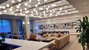 A modern hotel lobby with a central seating area, a long dining table, and a large window with natural light. - Luxury Rainey St Condo with rooftop pool, Lakeview & Gym (Austin)