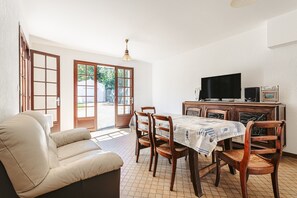 Un salon comprenant un canapé, une table à manger, des chaises, un téléviseur et un meuble.