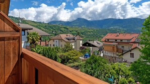 Ein Wohngebiet mit Häusern, einem Holzbalkon und einer Berglandschaft im Hintergrund.
