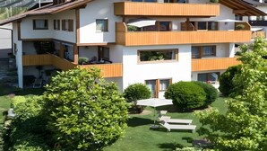 Ein mehrstöckiges Gebäude mit Balkonen, einem Garten und einem Poolbereich.