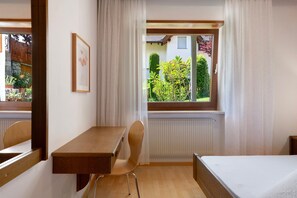 A room with a wooden desk, a chair, a bed, and a window with a view of greenery. - Apartment 'Hofanger Vinschgau' with Mountain View, Private Terrace and Wi-Fi (Algund)