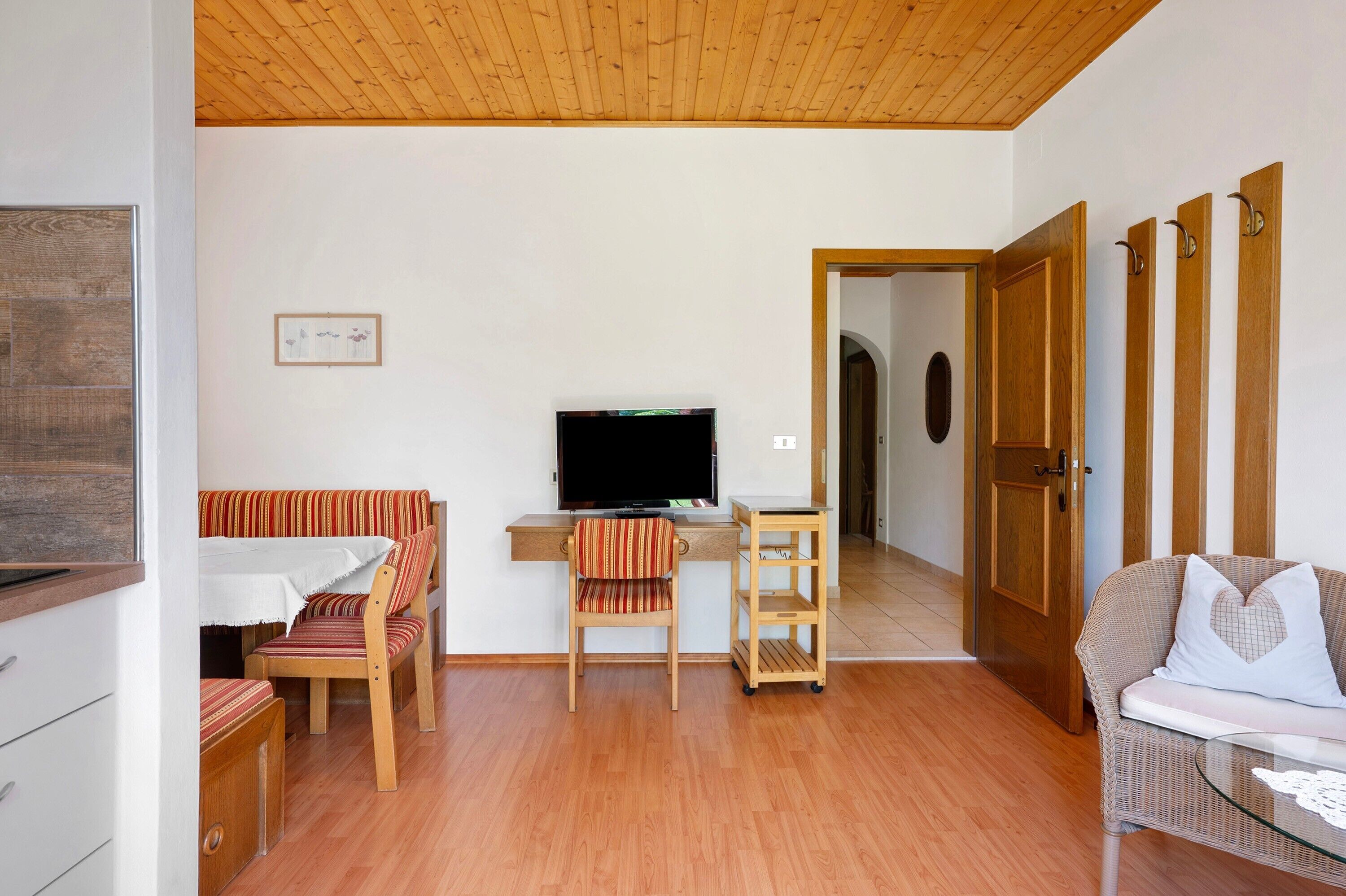 A living room with a television, wooden furniture, and a door leading to another room.