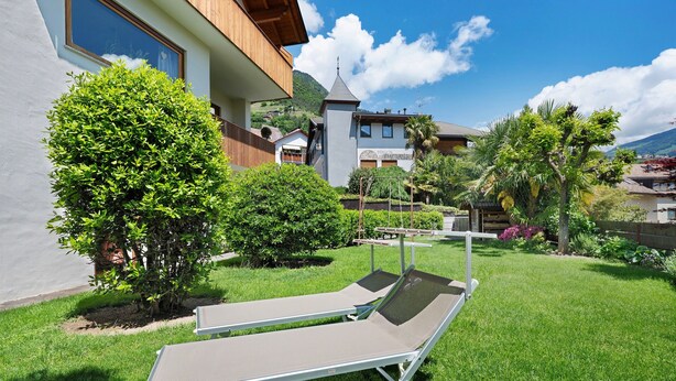 A modern building with a balcony, a well-maintained lawn, and a clear sky. - Apartment 'Hofanger Tirol' with Mountain View, Balcony and Wi-Fi (Algund)