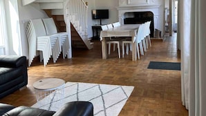 Un vaste espace de vie doté d’une cheminée, d’un escalier et d’un ensemble de meubles de salle à manger.