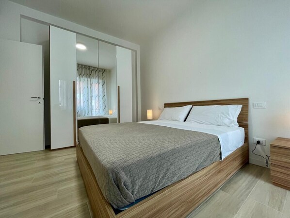 Un dormitorio con cama, cabecera de madera, mesita de noche, armario y espejo.