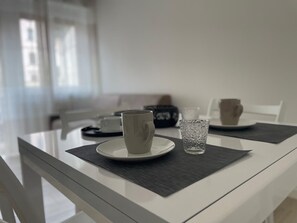 A dining table with two white plates, each with a cup and a glass.