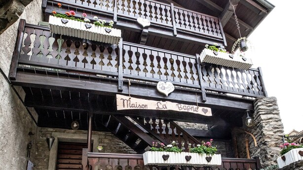 A multi-story building with balconies, stone walls, and flower boxes. - Studio 'Landa' with Balcony and Wi-Fi (Aosta)