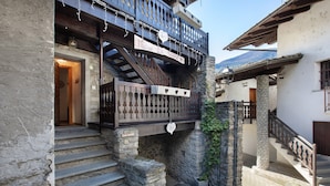 A traditional stone building with a wooden balcony, stone steps, and a sign reading 'Maison de la Boucle.' - Studio 'Landa' with Balcony and Wi-Fi (Aosta)