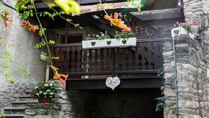 A stone building with balconies, a staircase, and hanging flower baskets. - Studio 'Landa' with Balcony and Wi-Fi (Aosta)