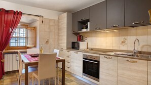 A modern kitchen with a dining area, featuring a microwave, oven, and a red curtain. - Studio 'Landa' with Balcony and Wi-Fi (Aosta)