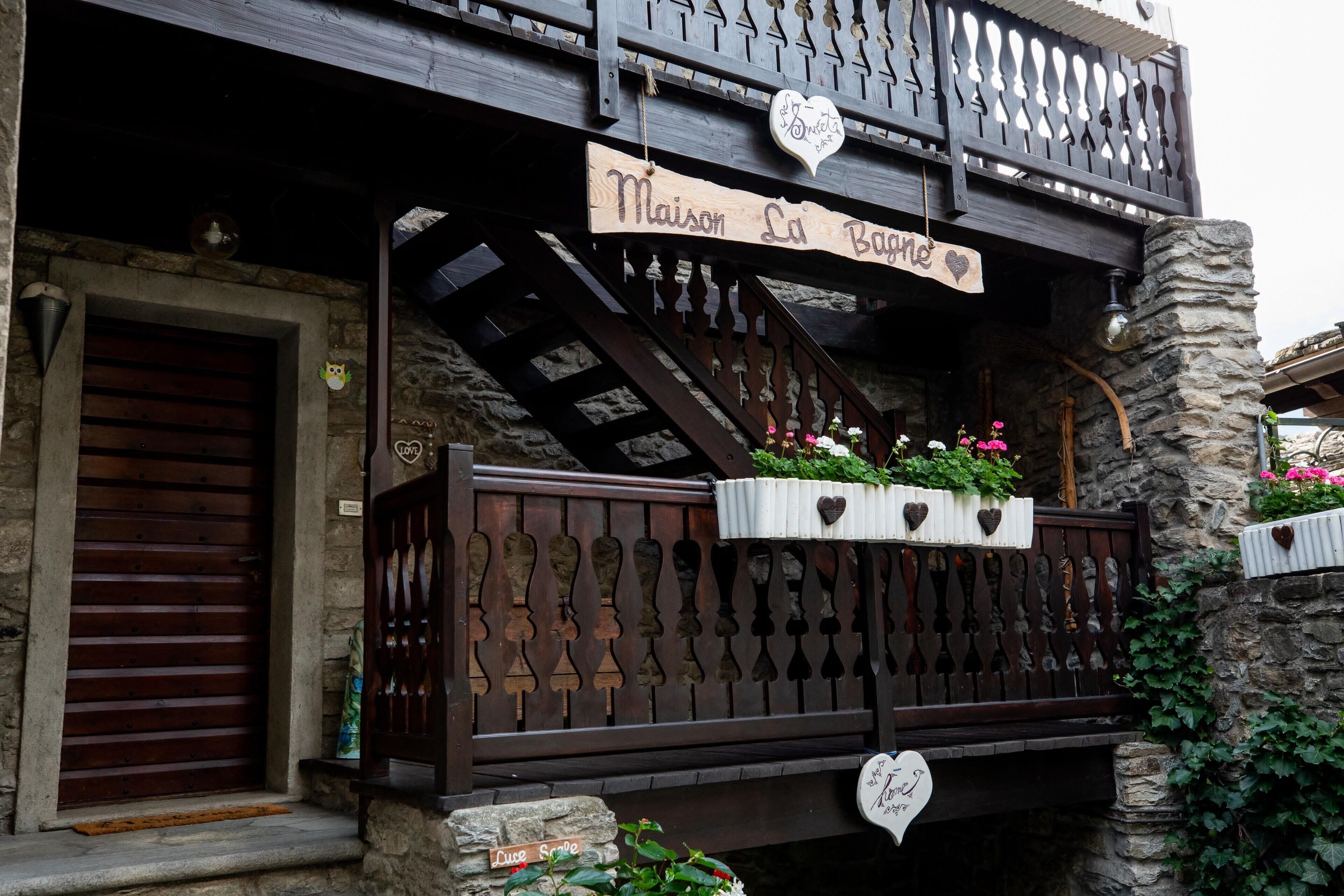 A wooden balcony with heart-shaped decorations, a stone wall, and a sign reading 'Maison La Borne.'