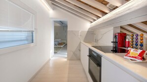 Cozinha moderna com bancada de mármore, forno embutido e janela com persianas.