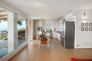 Una cucina moderna con zona pranzo, ampie finestre e vista sull'esterno.