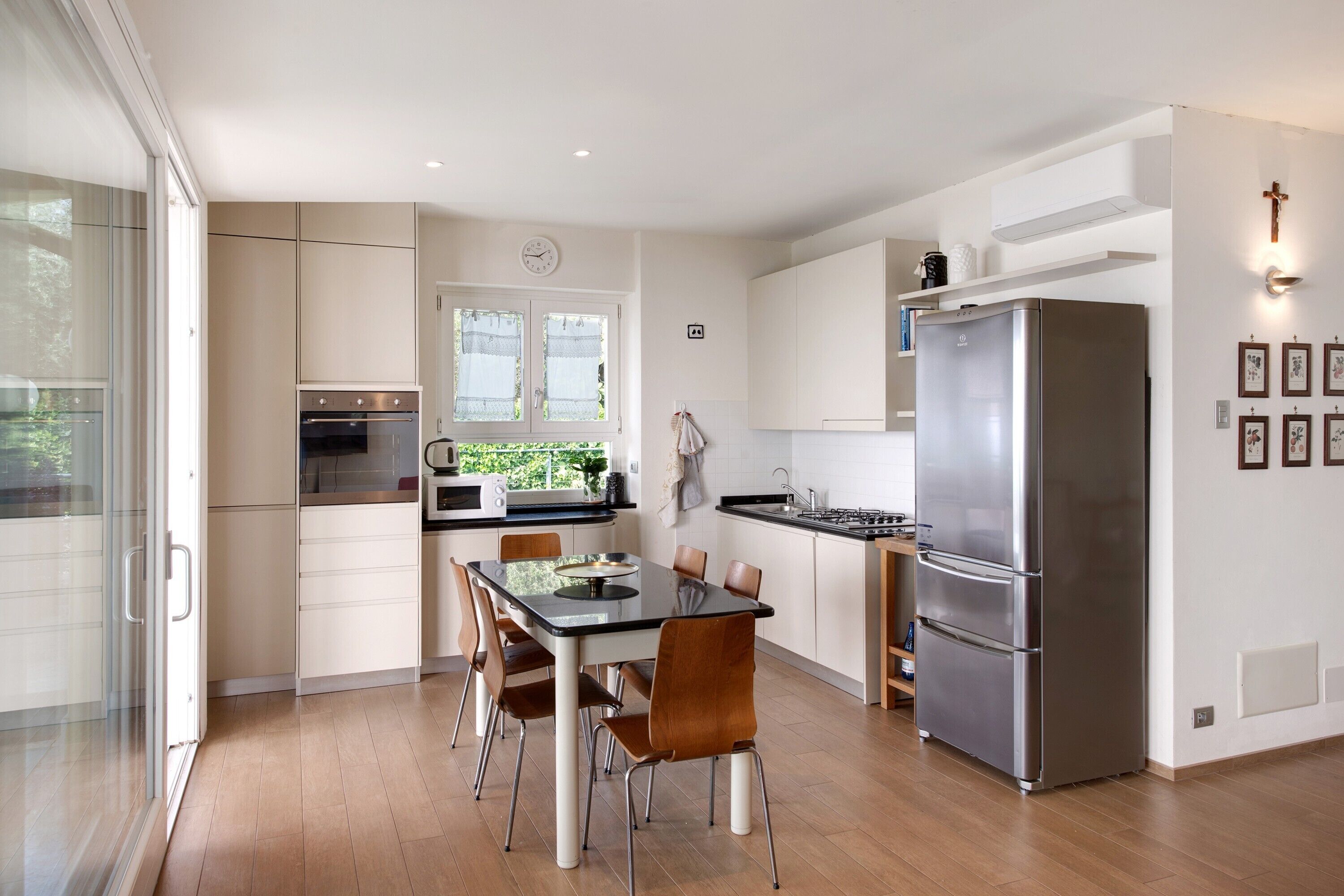 Una cocina moderna con una mesa de comedor, sillas, un refrigerador y una ventana con vistas.
