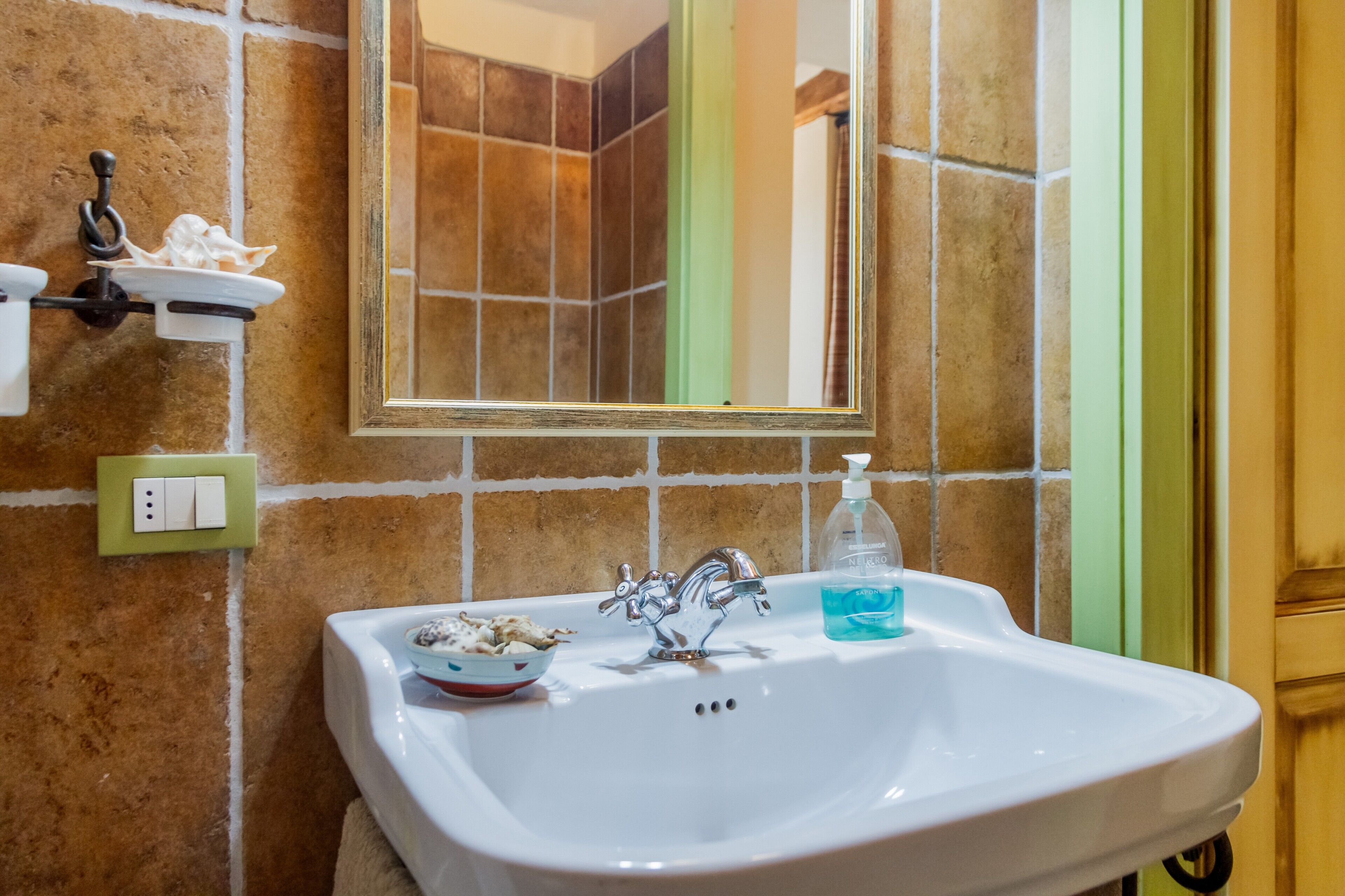A bathroom with a white sink, a mirror, a towel, and a soap dispenser.