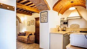 Une cuisine chaleureuse avec un plafond en bois, un lave-vaisselle encastré et un petit îlot central doté d’un évier.