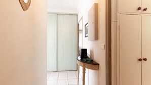 A hallway with a white door, a small table with a black object, and a cabinet with two handles.