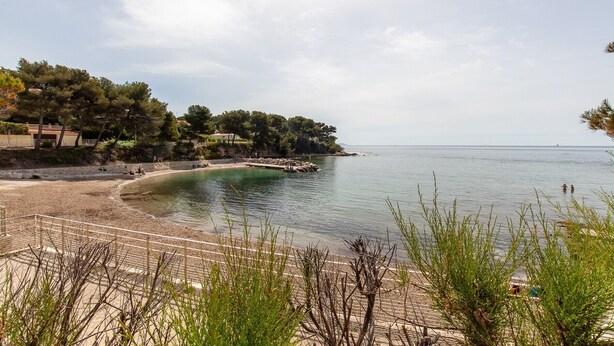 A coastal beach with a pebble beach, a wooden fence, and a rocky shoreline.