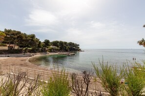 Une plage côtière avec un rivage de galets, une clôture en bois et une côte rocheuse.