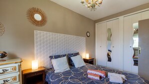 A bedroom with a bed, a dresser, a nightstand, a mirror, and a door with a unique design.