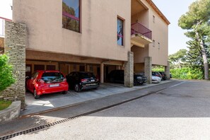 Un immeuble à plusieurs étages doté d’un garage, de piliers en pierre et d’un balcon.