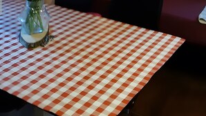 Une pièce avec une table à carreaux, un vase rempli de fleurs, un canapé avec des coussins rouges et une lampe.