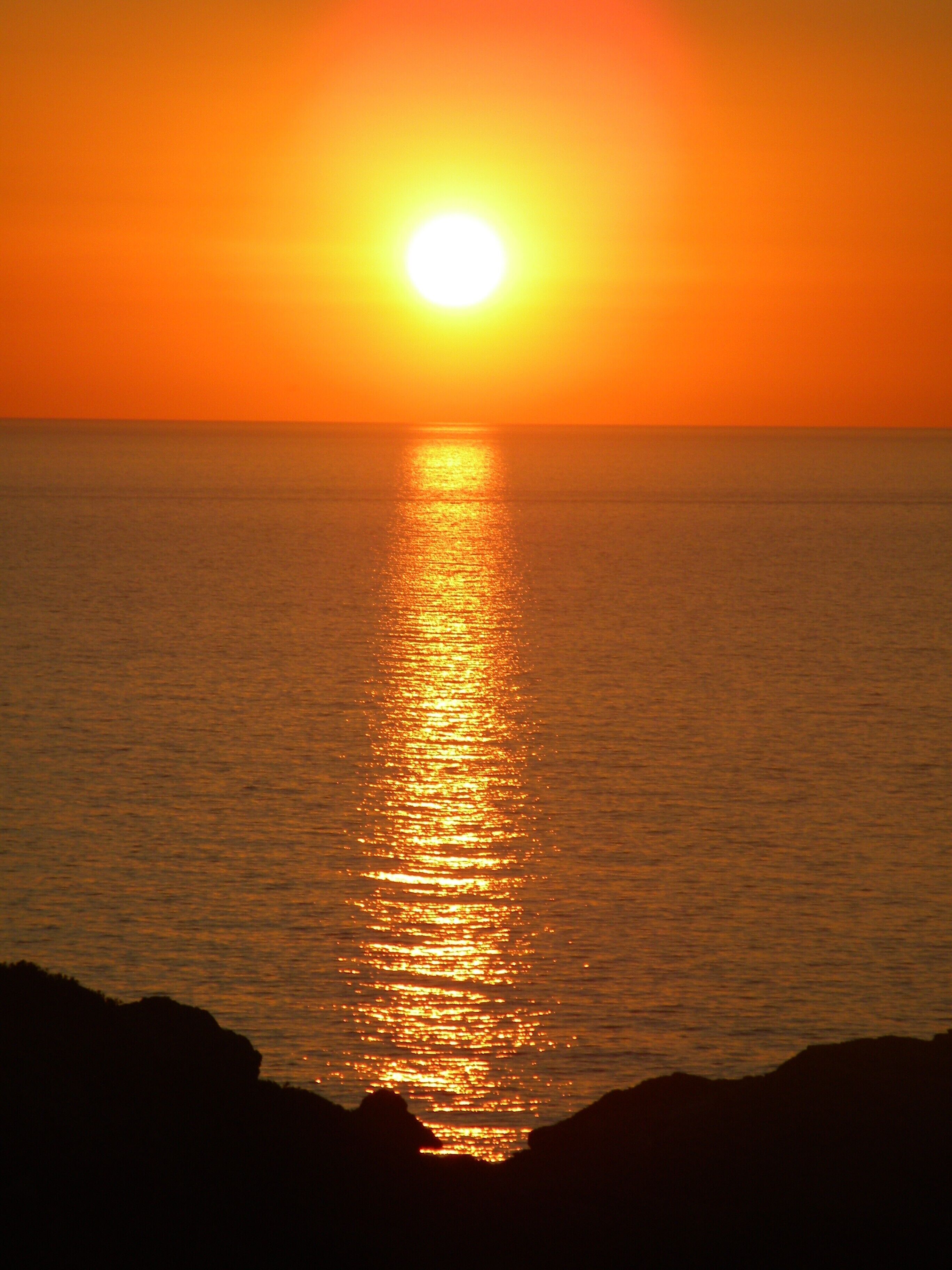 Un atardecer sobre el océano con un horizonte despejado.