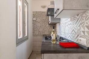 Een koelkast, een oven, een kookplaat, kookgerei, borden en bestek