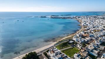 An aerial view of a coastal town with a beach, buildings, and boats.